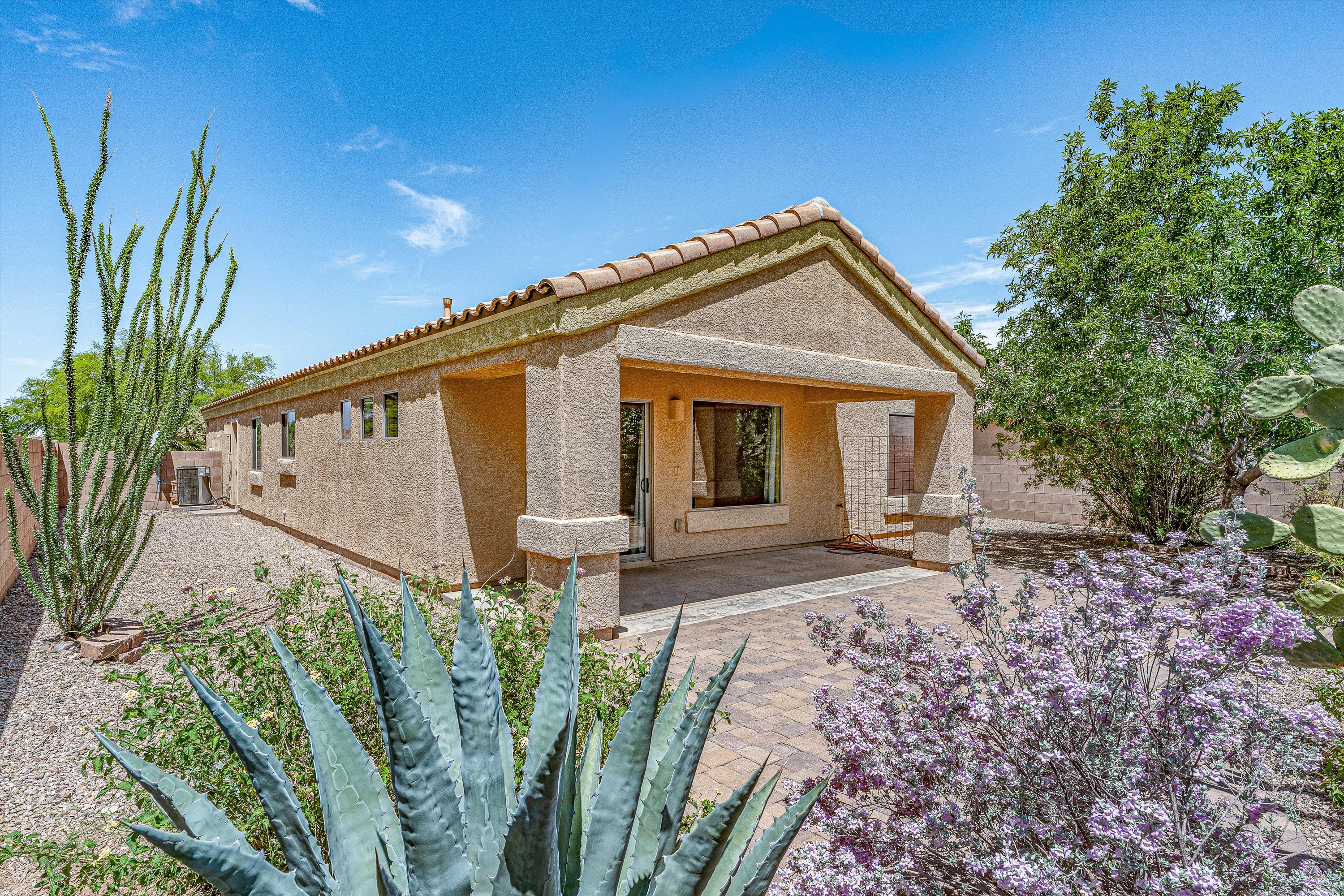 Back of 513 S Stone Bench Road in Corona de Tucson showing covered patio, paver hardscaping and landscaped backyard